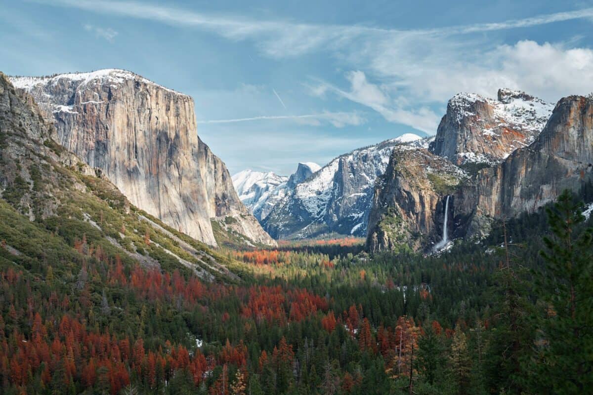 montagne entourée d'arbres sous ciel nuageux
