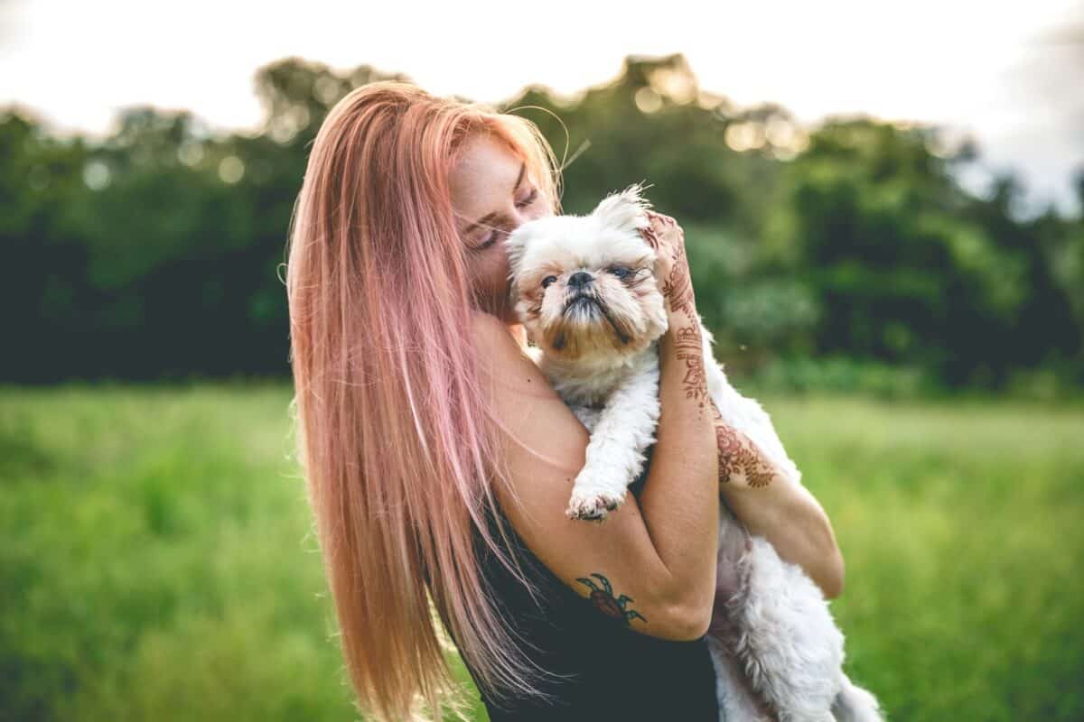 Une femme embrasse avec amour son chien moelleux dans un champ.