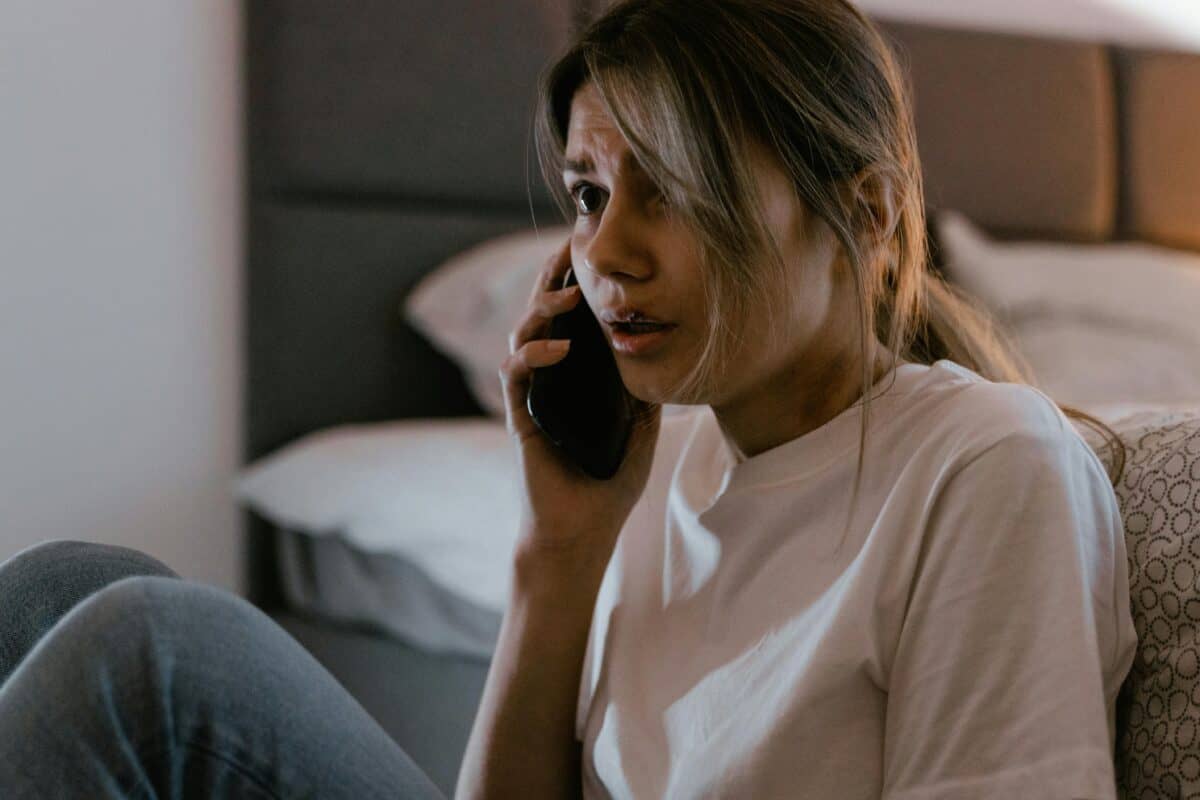 Une femme a l’air terrifiée lorsqu’elle appelle quelqu’un sur son téléphone.