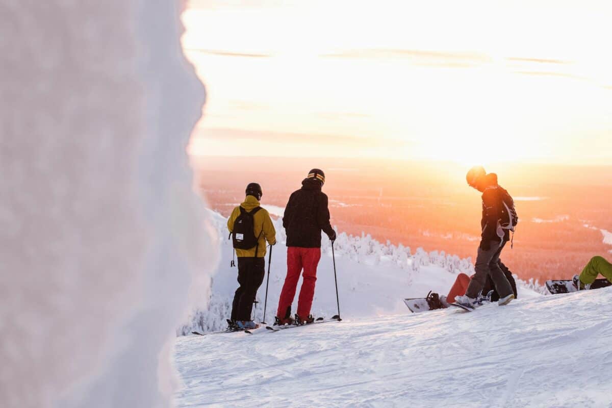 2 hommes en veste noire et rouge et pantalon noir debout sur un sol couvert de neige pendant