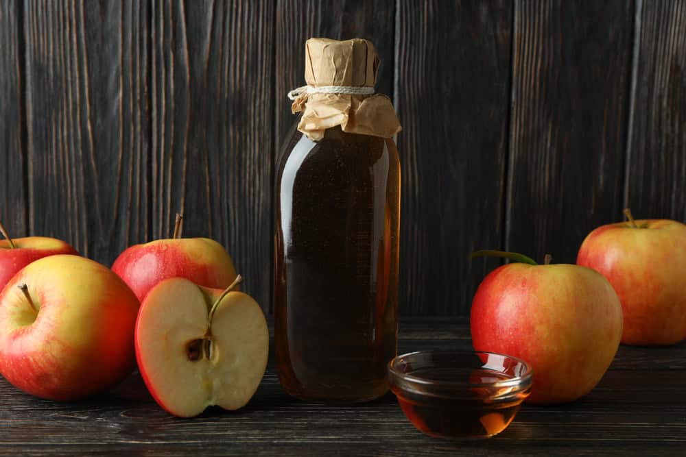 Vinaigre de pomme fait maison et ingrédients sur fond de bois