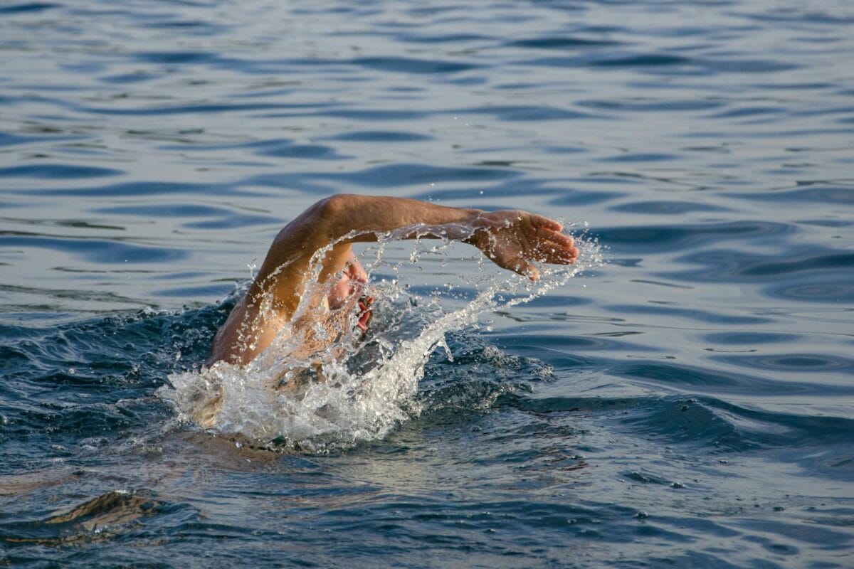 Un nageur effectuant une nage libre en eau libre, créant des éclaboussures.